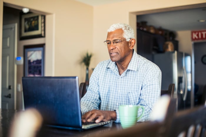 A person at a laptop in a home setting. 