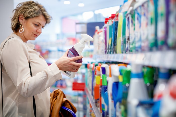 Someone in a store holding and looking at a cleaning supply.