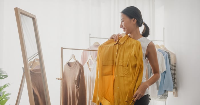 A person looks in the mirror while holding a shirt.