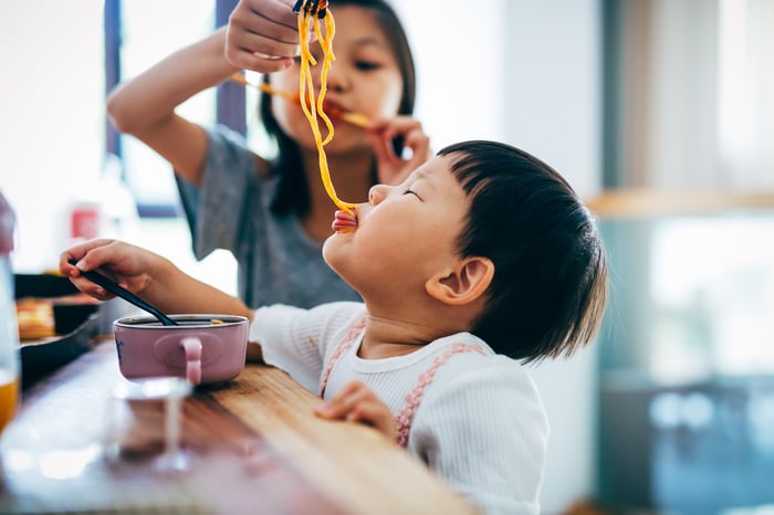 Two children eating noodles.