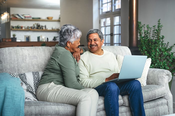 Two people sitting on a couch smiling at each other.