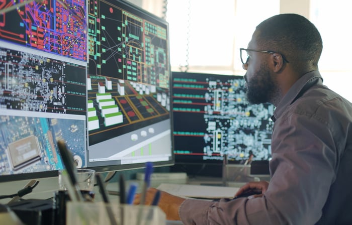 Semiconductor engineer working on product design using software on multiple monitors.