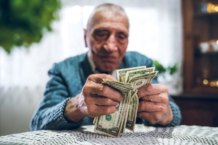 Person holding a pile of dollar bills.