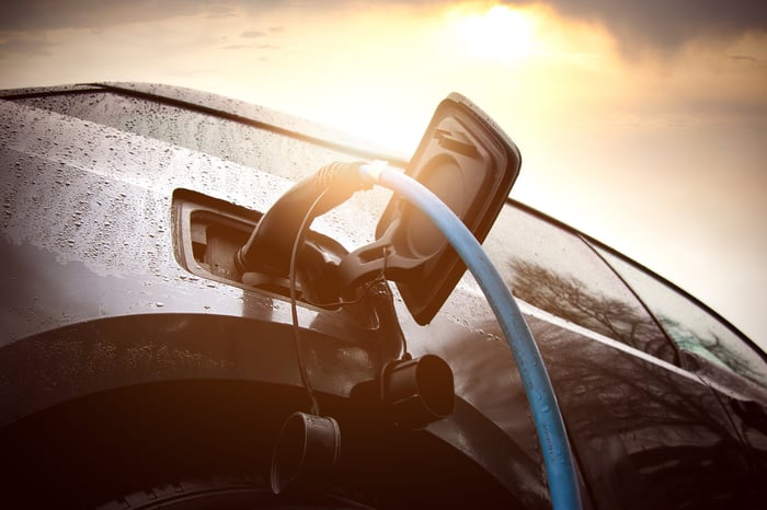 A worm’s eye view of a charger plugged into an electric vehicle with water droplets on the electric vehicle. 