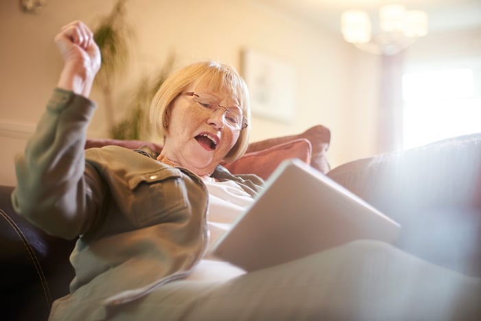 A person with a tablet and a look of happy surprise.