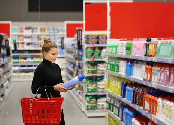 A person shopping at a store in the detergent aisle.
