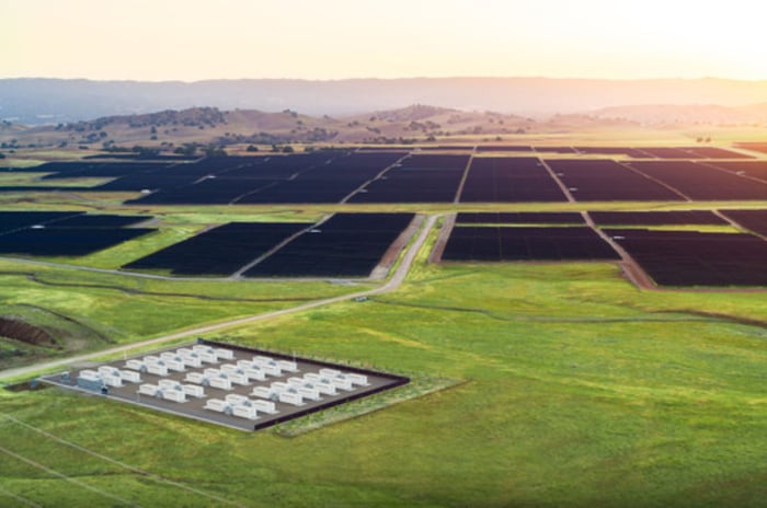 Tesla Megapacks in foreground, solar farm in background.