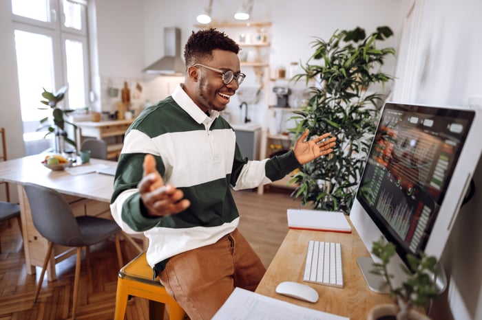 A person cheering while looking at graphs on a computer monitor. 