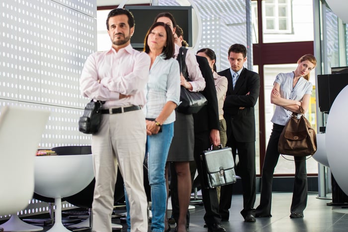 A group of people waiting impatiently in line in a bank.