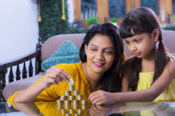 An adult and a child stacking coins in a family room.
