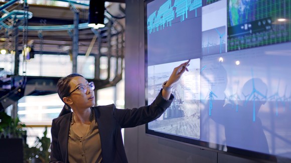 A person gives a presentation while pointing at different energy concepts on a large monitor.
