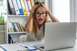 Person with hands on head and looking at a laptop (1)