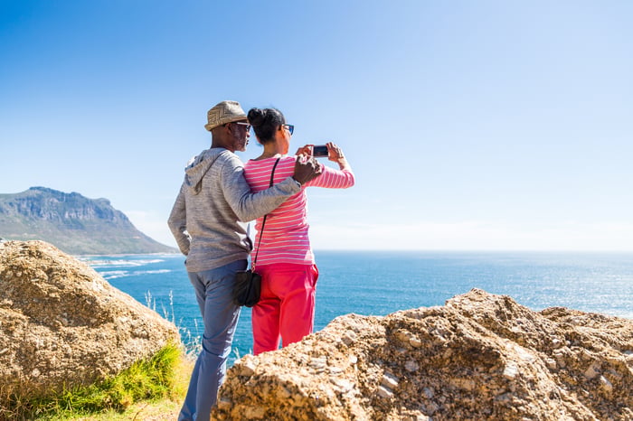 Two people looking out over the ocean and taking a photo.