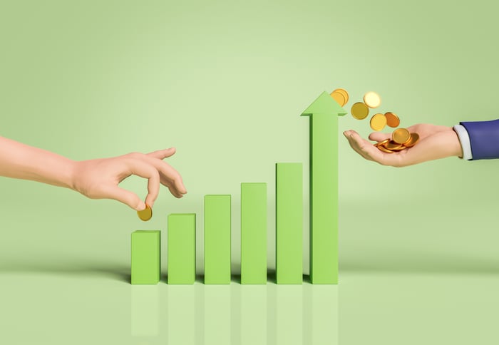 Person placing coin on green bar chart with more coins on the other end.