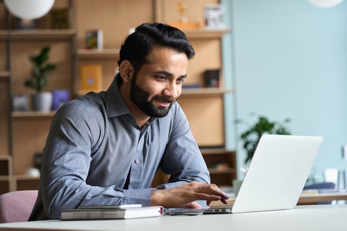 Person smiling and looking at a laptop.