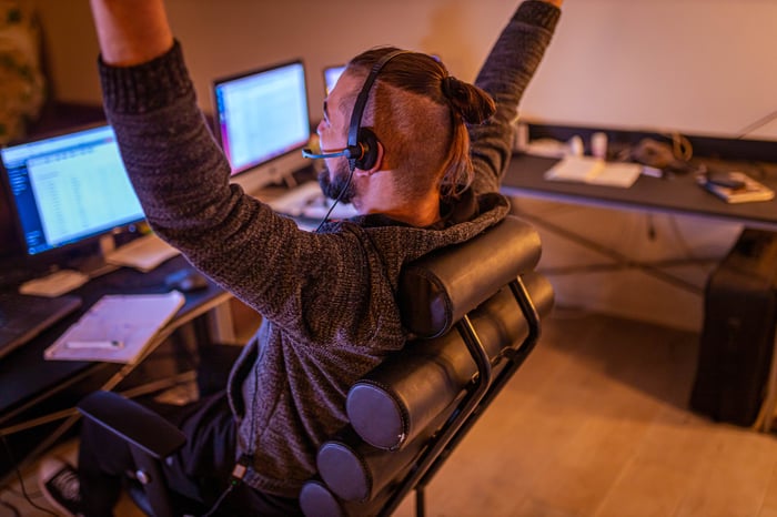 Person celebrating while trading on desktop computer.