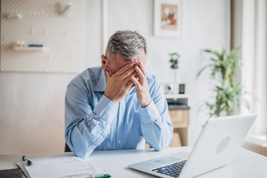 senior man laptop covering face GettyImages-1472263927