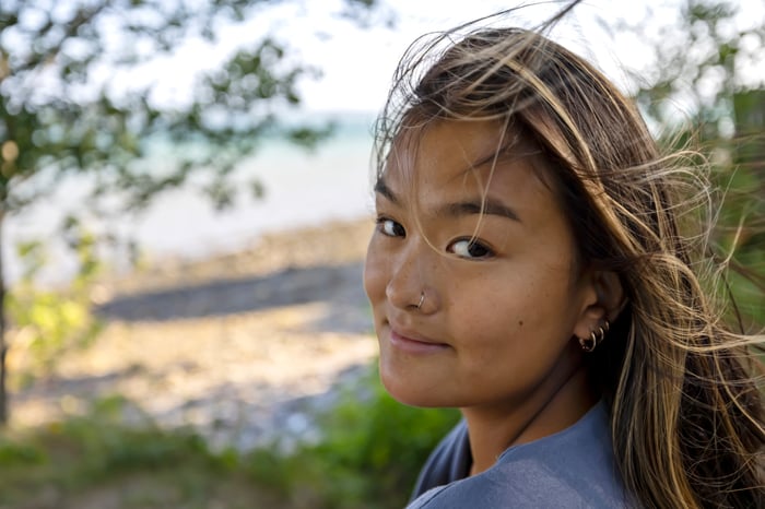 Person outside, looking at the camera and smiling slightly.