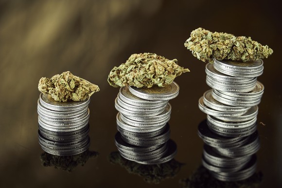 Cannabis buds atop stacks of coins.