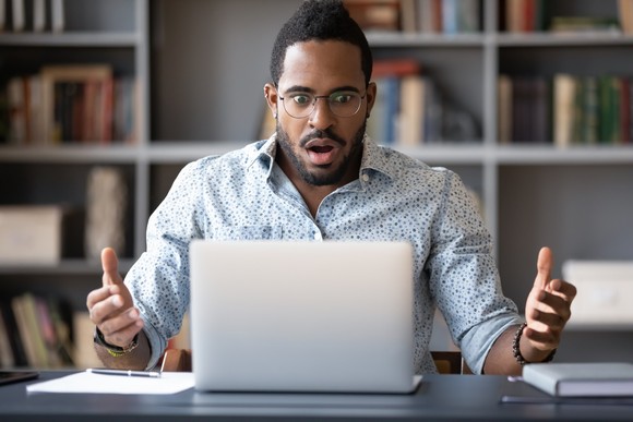 A person looking at a computer screen with a look of unpleasant surprise.