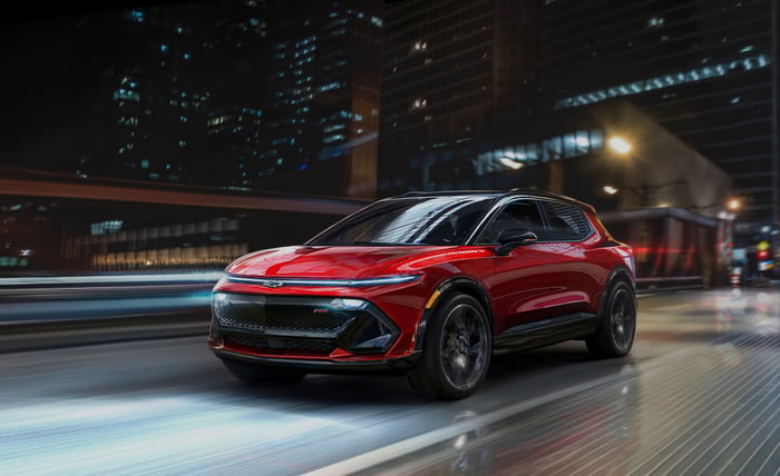 A rendering of a red Chevy Equinox EV driving a city street at night.