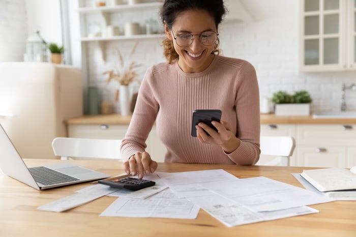 Smiling person looking at calculator.