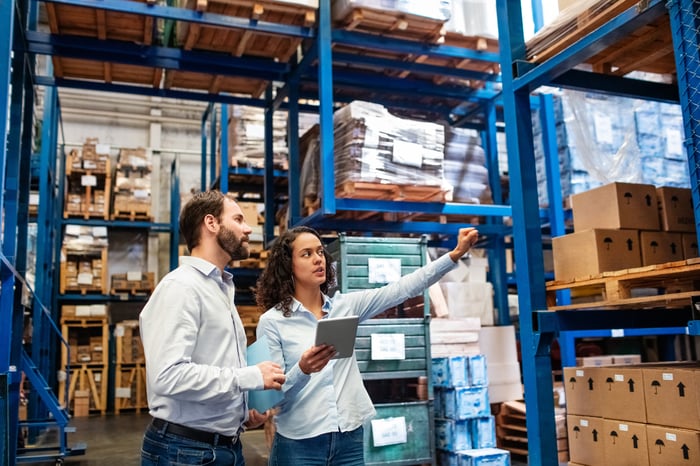 Two people in a logistics warehouse taking inventory.