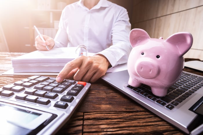 Person with a computer, piggy bank, and calculator.