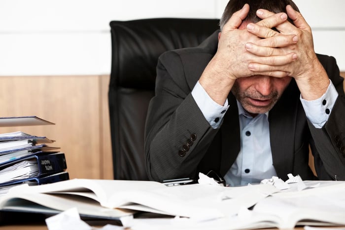 Person with head in hands at a desk.