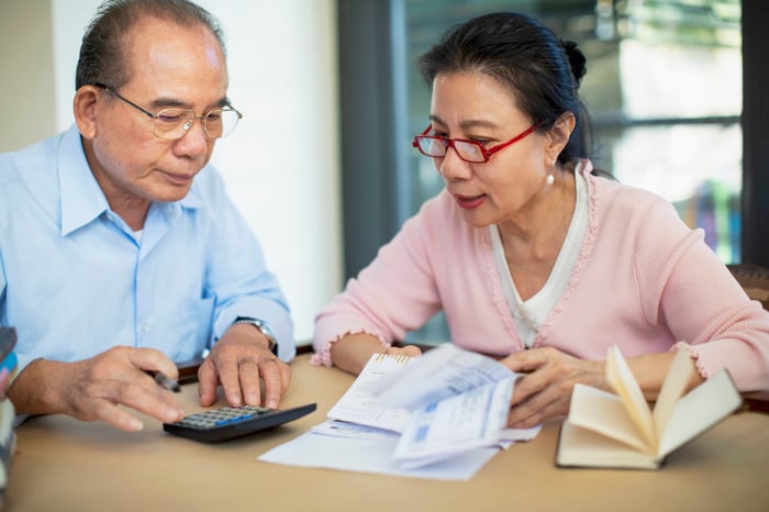 Two people looking at documents and a calculator.