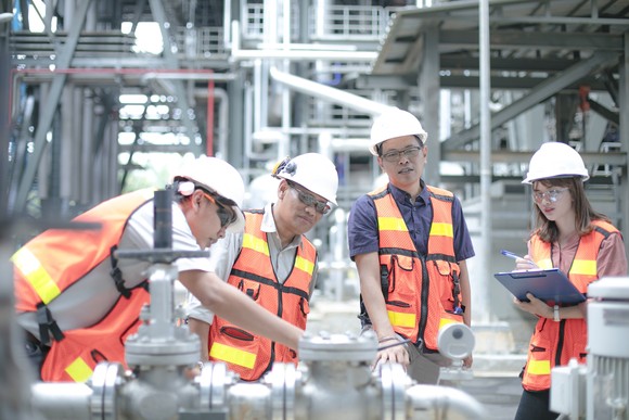 Four people in protective gear in an energy processing facility.