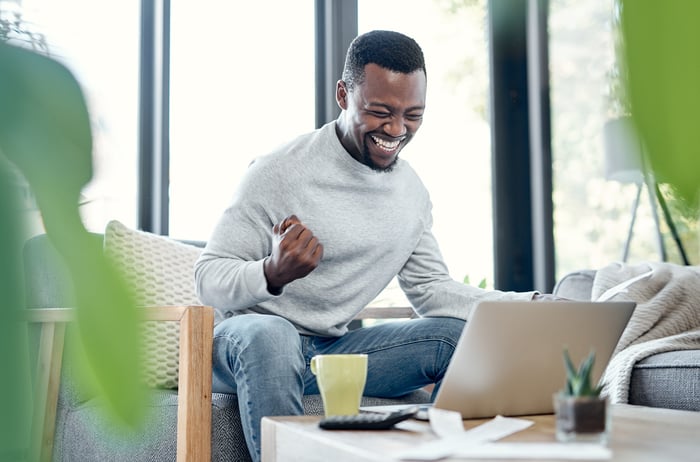 Person celebrating in front of laptop.