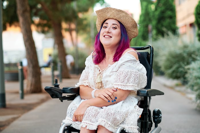 Person seated outdoors, smiling toward the camera.