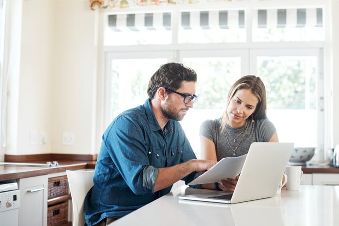 Couple discussing finances at kitchen island.