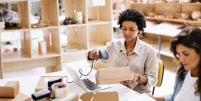 A person working on a laptop scans a package for delivery.