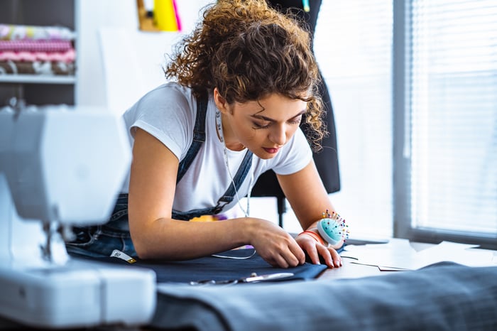 A person working on clothing near a sewing machine.