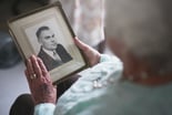 senior woman looking at an old black and white photo of a man