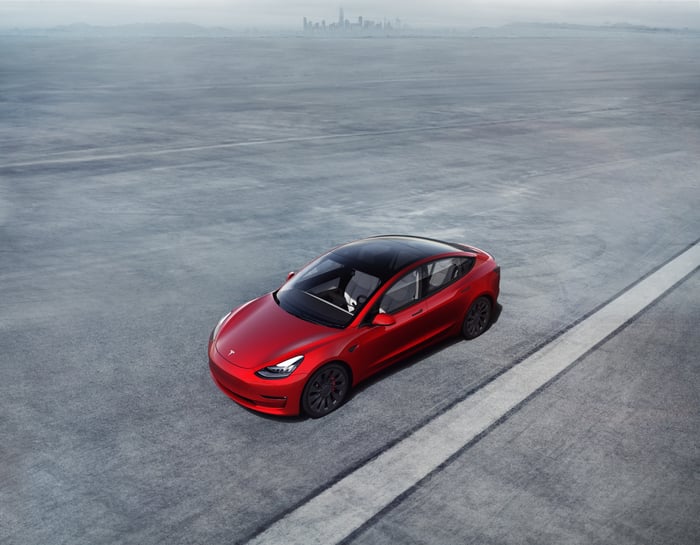 A Tesla Model 3 speeding along a deserted road.