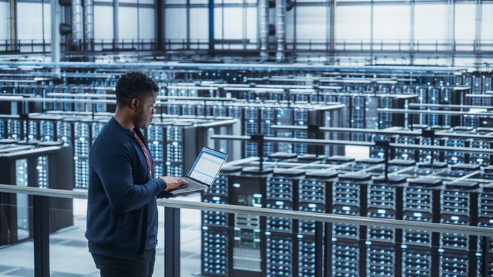 Engineer using laptop in crypto mining facility.