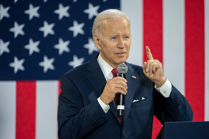 President Joe Biden delivering remarks with an oversized American flag behind him.