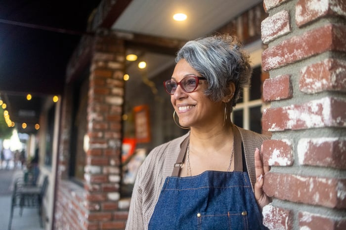A smiling person outside wearing an apron.