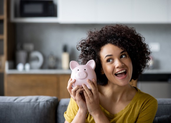 Happy person smiling and holding a piggy bank.