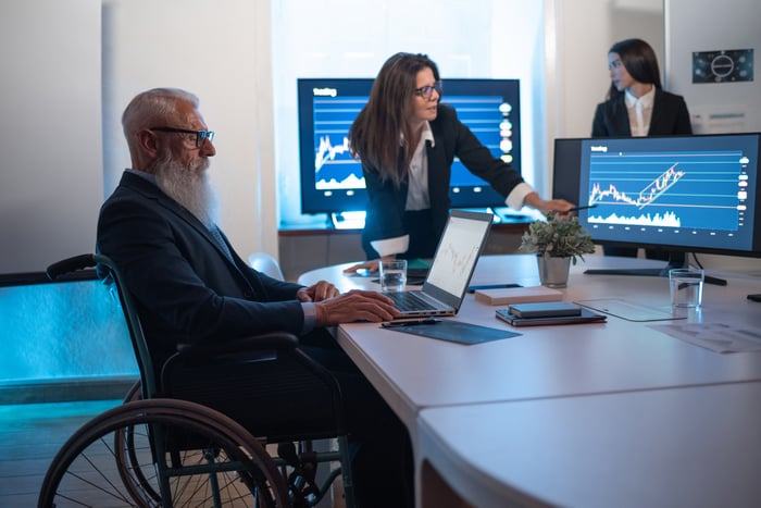 Two business people looking at stock charts and graphs on a computer.