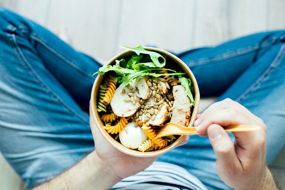 A person eating a salad out of a bowl.