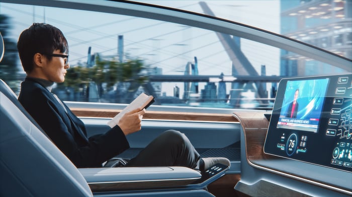 A person riding in a futuristic self-driving robotaxi.