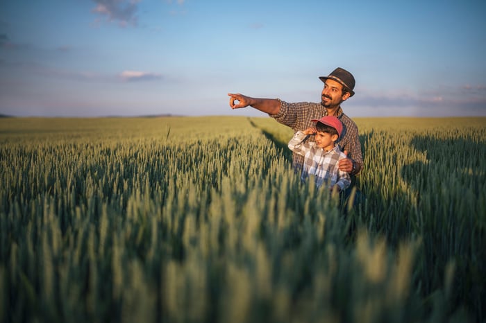 Man and boy in field and the man is pointing off to the distance.