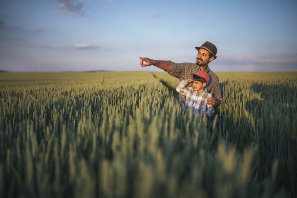 Man and boy in field and the man is pointing off to the distance.
