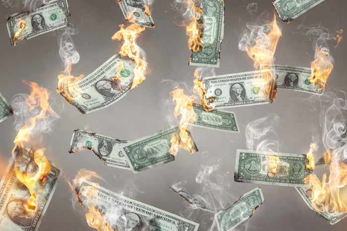 U.S. dollar banknotes on fire and falling down.