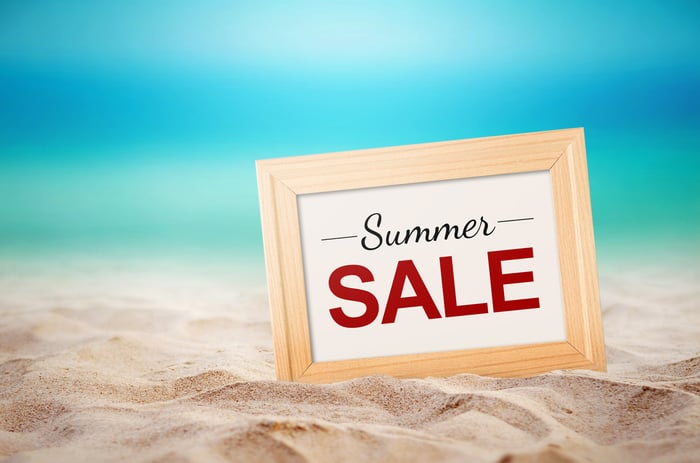 A sign that says Summer sale located on a beach.