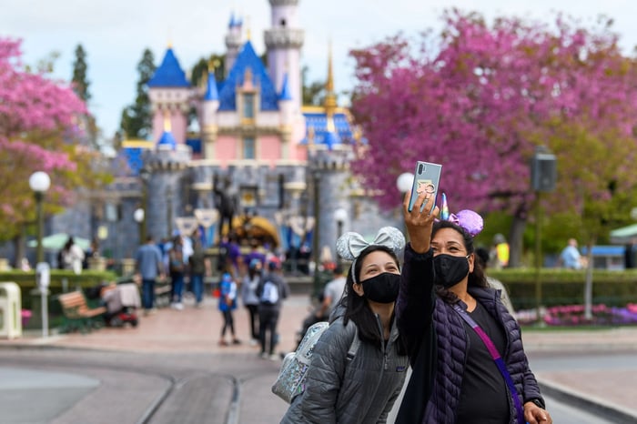 Tourists at Disneyland taking a photo in front of Sleeping Beauty Castle.